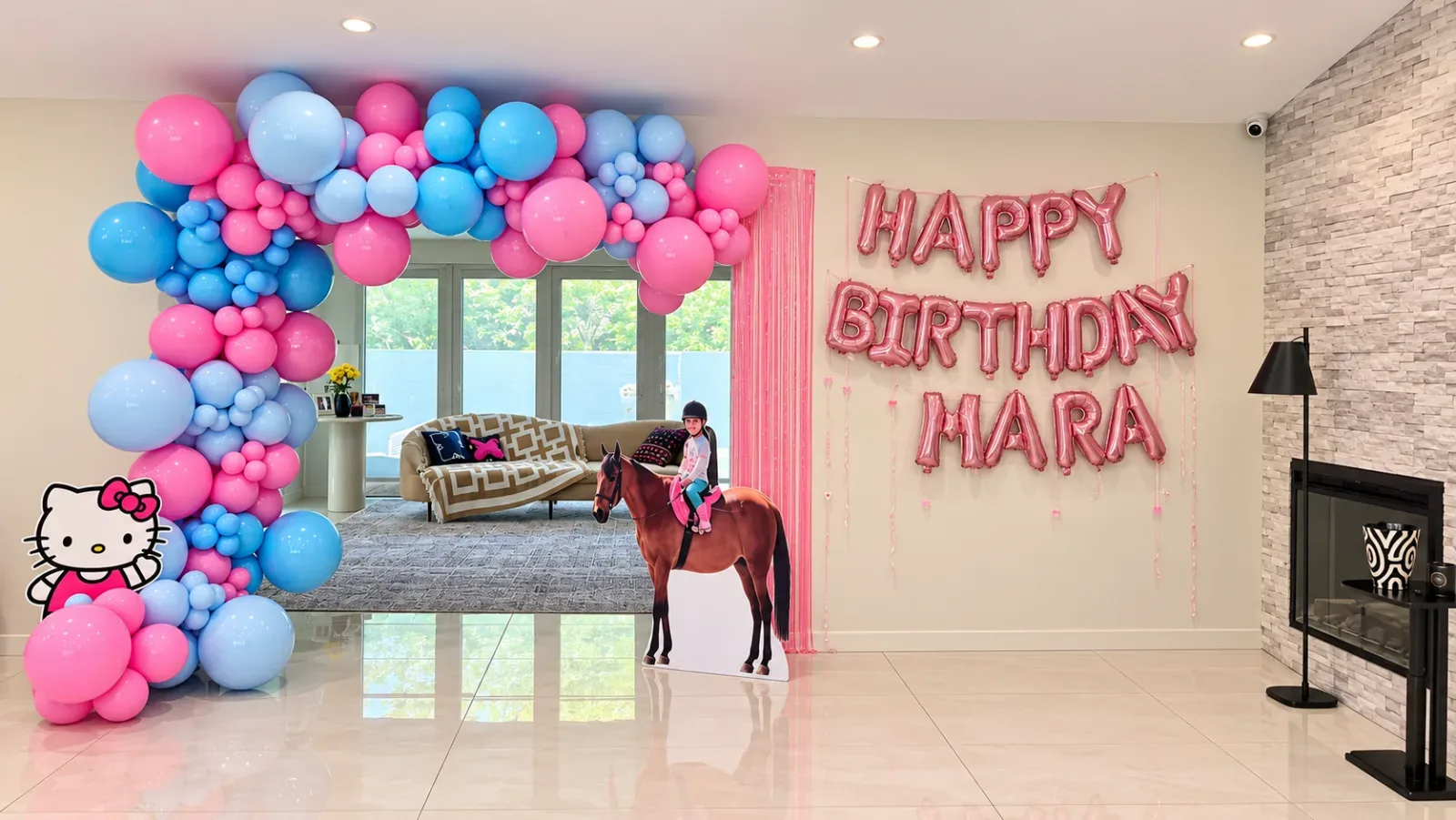 Hello Kitty birthday balloon decor in Woodland Hills with pink and blue organic balloon arch, personalized Happy Birthday foil letters and custom character cutouts.