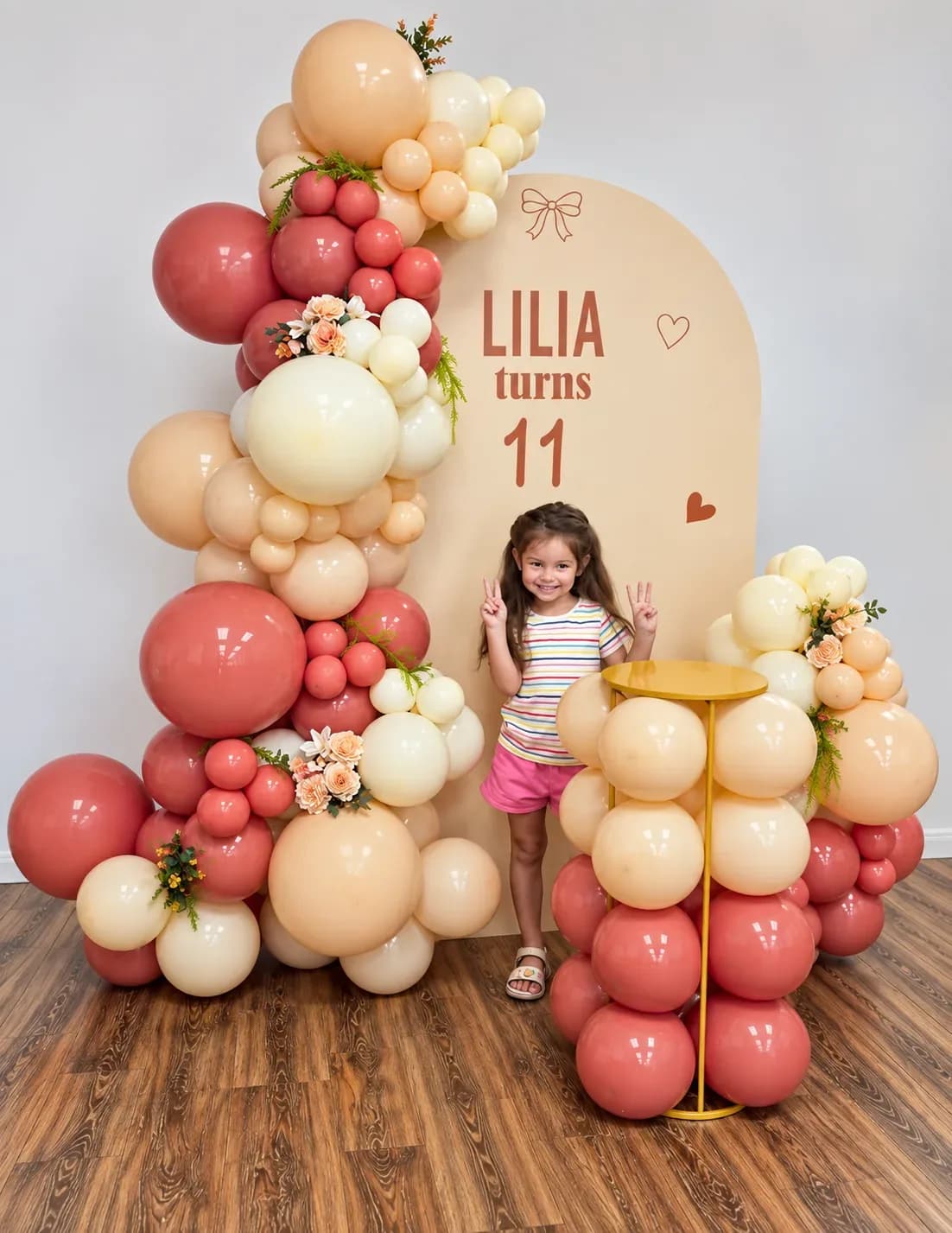 11th birthday balloon decor in Woodland Hills with personalized arch backdrop, organic terracotta peach and cream balloon garland, floral accents and decorated cake table
